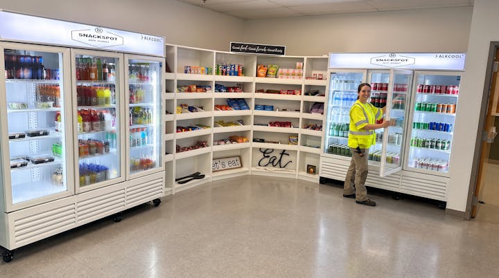 SnackSpot micro market with coolers, open shelving and a worker choosing a drink.